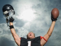football player holding helmet and ball above head